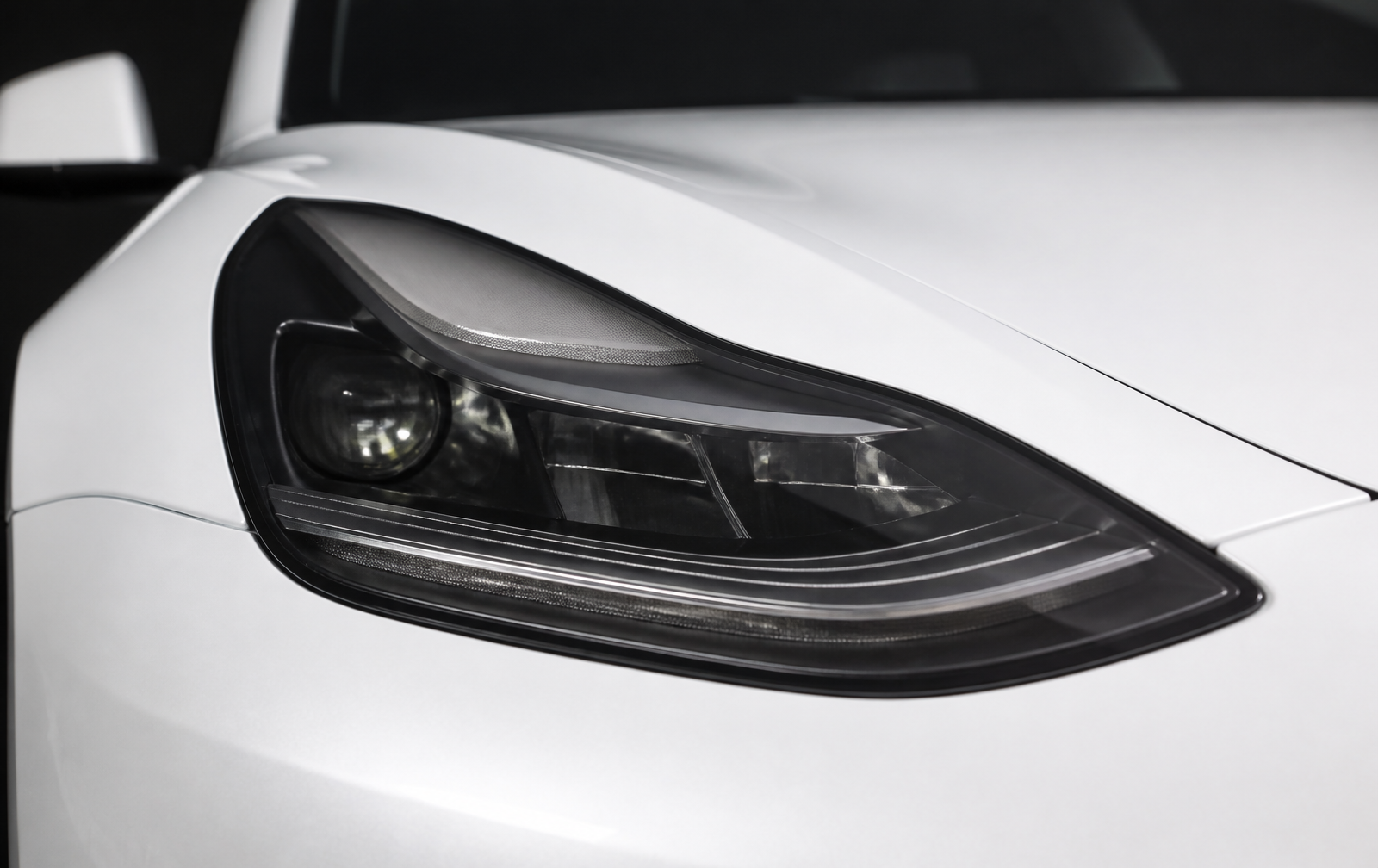 The identical headlight with neutral light smoke film applied only inside the lens boundary, with components still visible